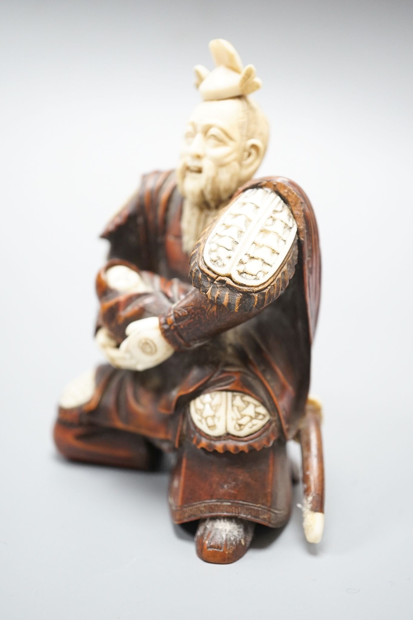 A Japanese wood and ivory okimono of a kneeling samurai holding a baby, Meiji period, unsigned, 12cm